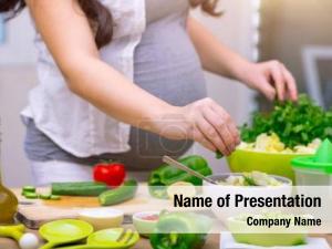 Happy pregnant woman cooking at home, doing fresh green salad, eating many different vegetables during pregnancy, healthy pregnancy concept