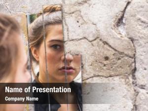 Teen girl looking at her reflection in the mirror fragments on the wall at street