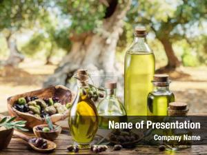 Olive oil and olive berries are on the wooden table under the olive tree