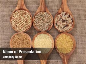 Cereal and grain selection of bulgur wheat, buckwheat, couscous, rye grain and brown and wild rice in olive wood spoons on hessian sacking 