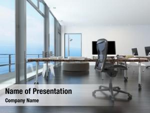 Modern waterfront office overlooking the sea with several computer workstations on movable wheeled office tables in a bright airy room with a glass view window or wall