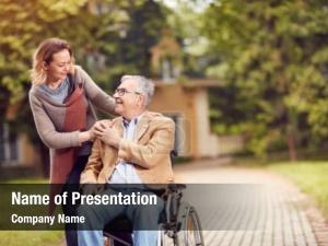 Senior man in wheelchair with happy caregiver daughter
