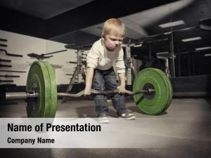 Determined young boy trying to lift a heavy weight bar