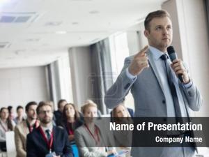 Businessman speaking through microphone during seminar in conven PowerPoint Template