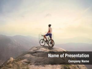 Peak cyclist standing over mountains